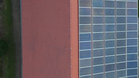 Aerial-Birds-Eye-View-Flying-Over-Red-Roof-With-One-Side-Covered-In-Solar-Panels