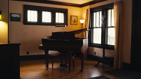 Un-Piano-De-Cola-Dentro-De-Una-Casa-Con-Pisos-De-Madera-Junto-A-Una-Ventana-Con-Una-Iluminación-Tenue