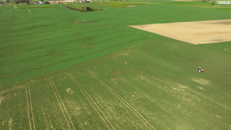 Aerial-View-Of-Tractor-Sprayer-On-Large-Green-Agricultural-Field