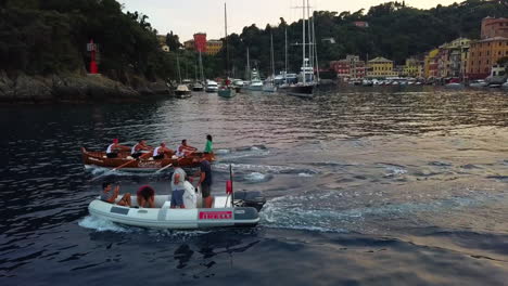 Aerial-tracking-shot-of-a-rowing-team-practicing-on-the-coast-of-Portofino,-suset-in-Italy