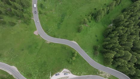 An-aerial-tilt-up-drone-shot-captures-multiple-cars-winding-along-the-roads-near-Selva-Pass-in-the-Dolomite-Mountains,-Trentino,-South-Tyrol,-Italy