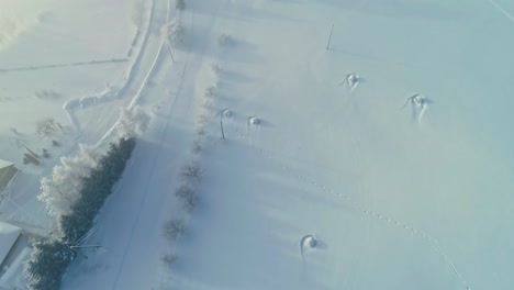 Schneebedecktes-Ackerland-Und-Kleine-Ortschaft,-Luftaufnahme-Einer-Drohne