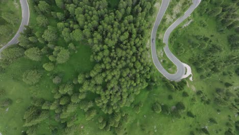 Aerial-overhead-view-of-vehicles-driving-on-the-winding-roads-as-the-drone-moves-forward-near-Selva-pass-Dolomites-Mountains,-Trentino,-South-Tyrol,-Italy