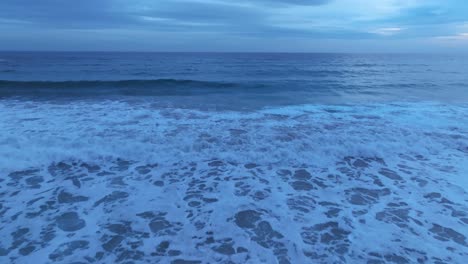 Blue-waves-of-Menorca-Spain,-aerial-drone-flying-closeup-above-the-ocean