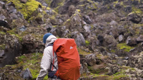 Backpacker-walking-on-rocky-ground,-on-a-summer-day,-in-Iceland---slow-motion,-Pan-shot