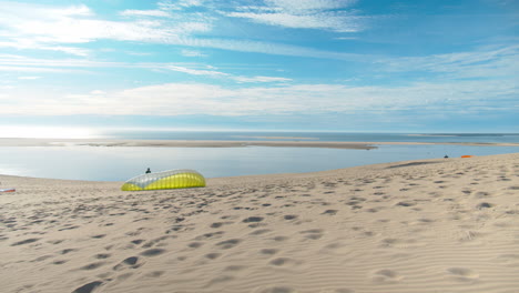 People-preparing-kites-on-sandy-dune-with-majestic-horizon-view,-pan-left-view