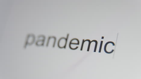 A-close-up-of-a-digital-screen-showing-a-text-cursor-and-"pandemic"-being-typed