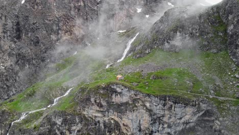 Cabin-In-Scenic-Valley-With-Huge-Waterfall-In-Cuneo,-Italy---Aerial-Drone-Shot