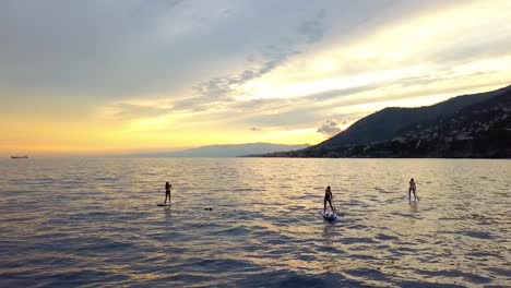 Vista-Aérea-De-Los-Practicantes-De-SUP,-Flotando-En-Aguas-Tranquilas-Del-Norte-De-Italia---Estática,-Disparo-De-Drones