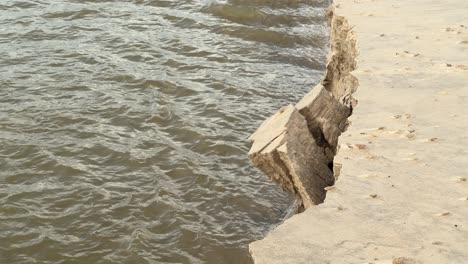 El-Agua-Fluye-Junto-A-Un-Deslizamiento-De-Tierra,-Revelando-Signos-Evidentes-De-Erosión-Dentro-Del-Paisaje-Natural.