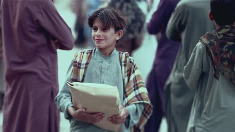 Front-view-of-young-Pakistani-boy-happy-after-receiving-food-from-Iftar-drive-in-Balochistan,-Pakistan