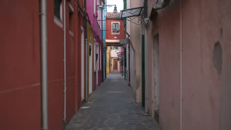Handheld-Shot-of-Colorful-Alleyway-Between-Historic-Buildings,-Burano-Island,-Venice-Daytime