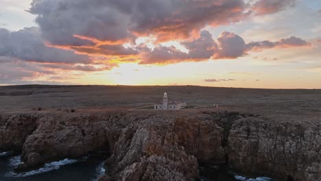 Punta-Nati-Lighthouse,-north-of-Menorca-Spain-Gradient-pale-tones-skyline-cliff-rocky-shore-sea-landscape-aerial-drone-view