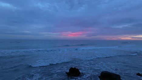 Horizonte-De-Puesta-De-Sol,-Primer-Plano-De-Las-Olas-Que-Llegan-A-La-Costa-Mediterránea-De-Menorca-Fondo-De-Cielo-Rosa