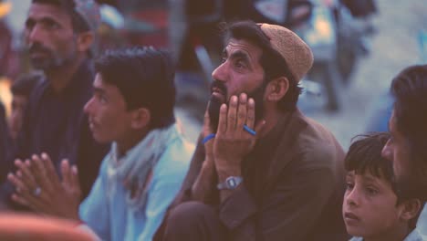 Profile-view-of-a-Pakistani-man-with-his-family-waiting-for-food-in-Balochistan,-Pakistan