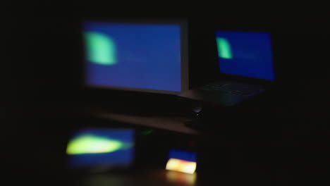 A-side-angle-with-selective-focus-of-four-digital-computer-device-screens-displaying-a-strobing-pattern-in-a-dark-room