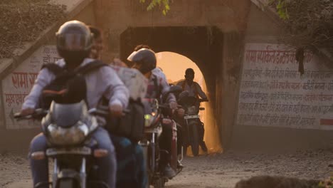 Motor-bike-and-scooter-traffic-coming-out-of-a-railway-underpass-with-golden-sunlight-in-Gwalior-India