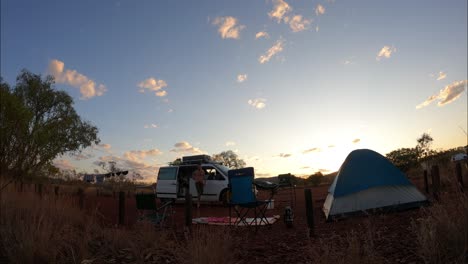 Time-lapse-shot-of-couple-relaxing-in-desert-national-park-with-tent-during-golden-sunset