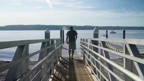 Man-walking-out-onto-a-public-dock-on-a-sunny-day