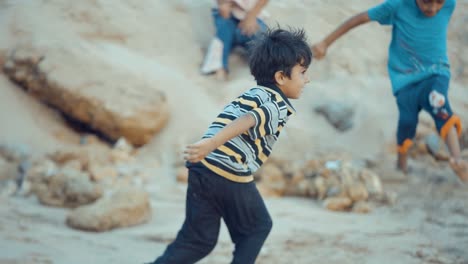 Kleiner-Junge-Spielt-Mit-Sand-In-Den-Händen,-Bevor-Er-Am-Strand-In-Belutschistan-Davonläuft