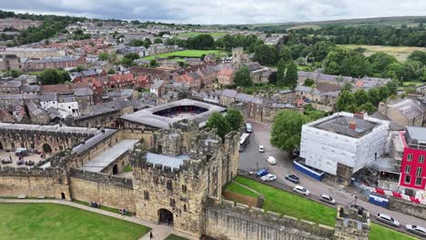 Alnwick,-Inglaterra,-Reino-Unido,-Vista-Aérea-De-Las-Murallas-Del-Castillo-Medieval,-Edificios-De-La-Ciudad-Y-Tráfico-Callejero,-Disparo-De-Drone