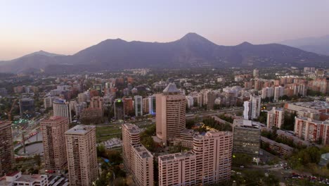 Drone-Andean-cordillera-mountain-range-valley-city-at-Santiago-de-Chile-Vitacura-and-Las-Condes-neighborhoods,-aerial-view-with-dusk-colorful-sunset-skyline