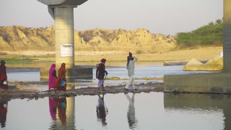 Pilger-Oder-Eine-Gruppe-Von-Dorfbewohnern-Der-Bundelkhand-Kultur,-Die-Am-Ufer-Eines-Sindh-Flusses-Unter-Einer-Brücke-Spazieren