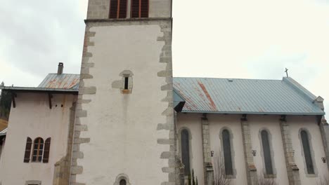 Tilt-shot-of-the-tower-of-the-Church-Notre-Dame-de-la-Nativité-in-Les-Gets,-France