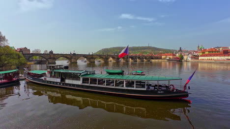 -Quaint-boat-gently-floats-upon-shimmering-water-surface-against-backdrop-of-iconic-Charles-Bridge