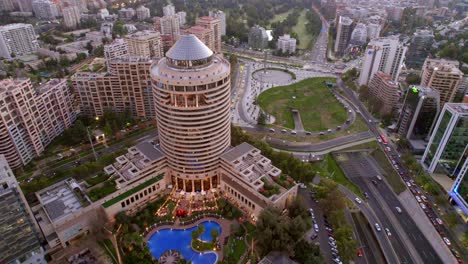 Paisaje-Urbano-Panorámico-Aéreo-De-Santiago-De-Chile-Nueva-Zona-Urbana-De-Las-Condes,-Tráfico-Alrededor-Del-Hotel-Mandarin-Ortiental-Y-Parque-Schneider,-Vista-De-Drones