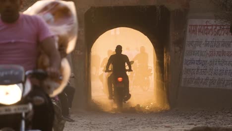 Motor-bike-and-scooter-traffic-coming-out-of-a-railway-underpass-with-golden-sunlight-in-Gwalior-India