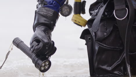 Telephoto-slomo-shot-of-water-dripping-of-ice-diver's-hand-gripping-a-torch