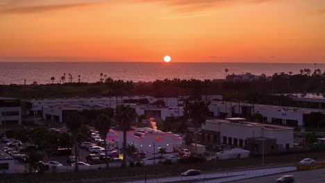 Drohnen-Hyperlapse-Des-In-N-Out-Burger-Standorts-In-Carlsbad,-Kalifornien,-Während-Des-Sonnenuntergangs-Mit-Dem-Pazifischen-Ozean-Und-Stetigem-Fahrzeugfluss-Durch-Die-Drive-Thru-Spur