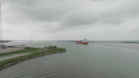 An-aerial,-following-shot-captures-an-oil-tanker-steaming-past-Morgan's-Point-on-the-Houston-Ship-Channel-under-gloomy-skies-in-Houston,-Texas