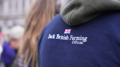 In-slow-motion-a-person-wears-a-blue-fleece-top-with-the-words-on-the-back-that-read,-“Back-British-Farming”