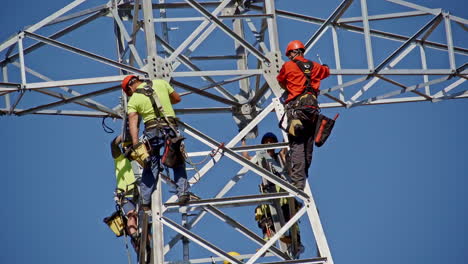 Engineers-on-Electric-Pylon-Tower-Working-on-New-Power-Grid-Installation,-Slow-Motion