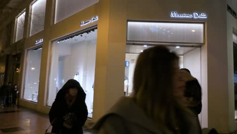 Pedestrians-and-shoppers-walk-past-the-Spanish-clothing-manufacturing-and-brand-Massimo-Dutti-store-during-nighttime-in-Madrid,-Spain