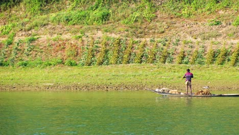 Man-paddles-flat-bottom-canoe-with-long-oar-while-young-boy-stands-on-boat