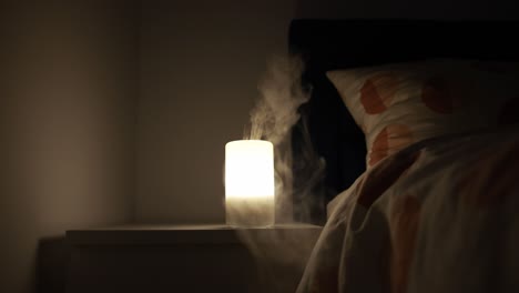 Static-shot-of-an-essential-oil-diffuser-on-a-nightstand-emitting-a-warm-light