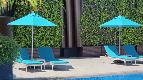 Empty-deck-chairs-and-umbrellas-by-the-swimming-pool