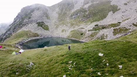 Nature-Adventure--Hiker-Amidst-Lush-Mountain-Vegetation,-Gazing-at-Scenic-Lake-Iezer-in-Romania's-Majestic-Outdoors