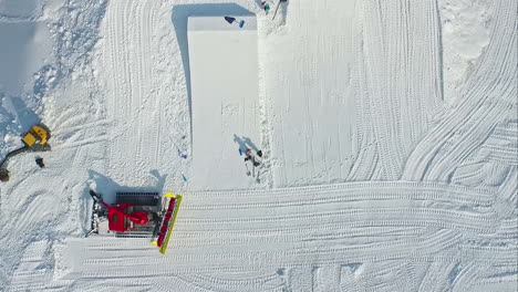 -Snowplow-making-ski-and-snowboard-jumps-at-a-ski-resort---straight-down-aerial-view