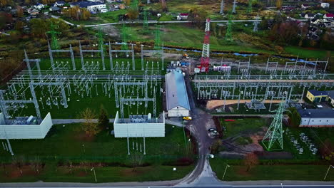 Vista-Aérea-De-La-Moderna-Subestación-Eléctrica,-Sistema-De-Distribución-De-Electricidad-Y-Tráfico-Por-Carretera-Rural.