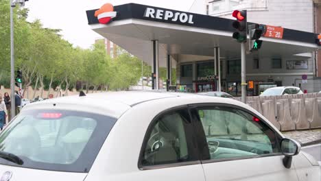 Un-Coche-Detenido-En-Un-Semáforo-En-España,-Frente-A-Una-Gasolinera-Propiedad-De-Repsol,-La-Compañía-Española-De-Energía-Petroquímica-Y-Combustibles-Fósiles.