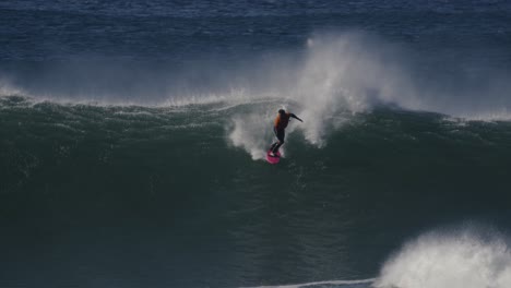 Slow-motion-shot-of-a-surfer-riding-a-wave-breaking-into-a-huge-mass-of-white-foam