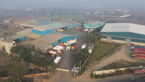 Vista-Aérea-Del-Dron,-La-Cámara-Del-Dron-Se-Mueve-Hacia-Un-Lado-Y-Muestra-Una-Gran-Fábrica-Y-Se-Están-Cargando-Camiones-En-La-Fábrica-Y-Se-Están-Pesando-Los-Camiones-Cargados