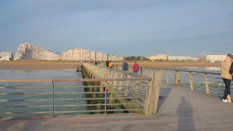 Gente-Vestida-De-Invierno-En-El-Muelle-De-Madera-De-La-Ciudad-En-La-Costa-Del-Mar-En-Un-Día-Frío