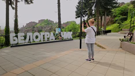 Female-tourist-takes-photo-of-town-sign-written-in-large-Cyrillic-typography-letters