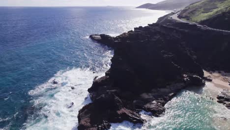 aerial-footage-circling-around-a-rocky-peninsula-as-white-capped-waves-of-the-Pacific-ocean-crash-along-the-rocky-shore-as-the-turquoise-water-sits-peacefully-in-the-secluded-Halona-Beach-cove