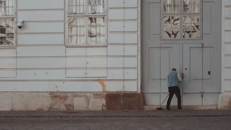 Person-Cleaning-Gate-Of-Austrian-National-Library,-State-Hall-While-Tourist-Passing